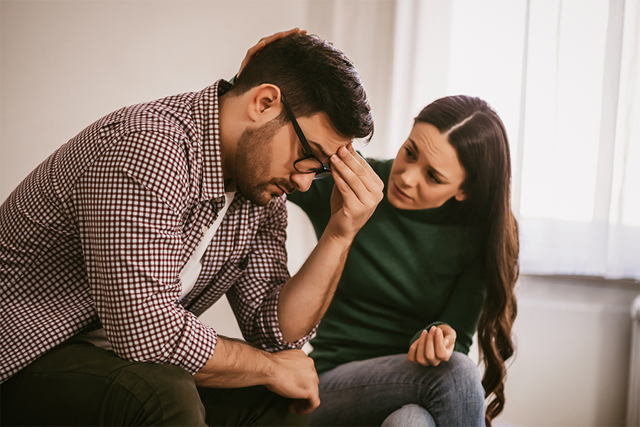 A concerned woman comforting a distressed man, illustrating how to get someone into alcohol rehab with empathy and support