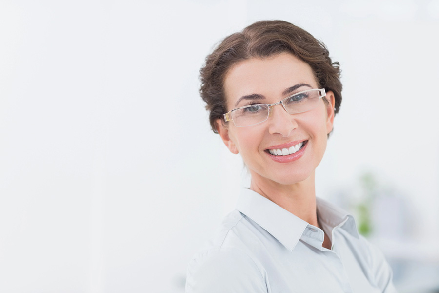 A confident, smiling woman in a bright setting, symbolizing recovery and strength after being healed from childhood trauma.