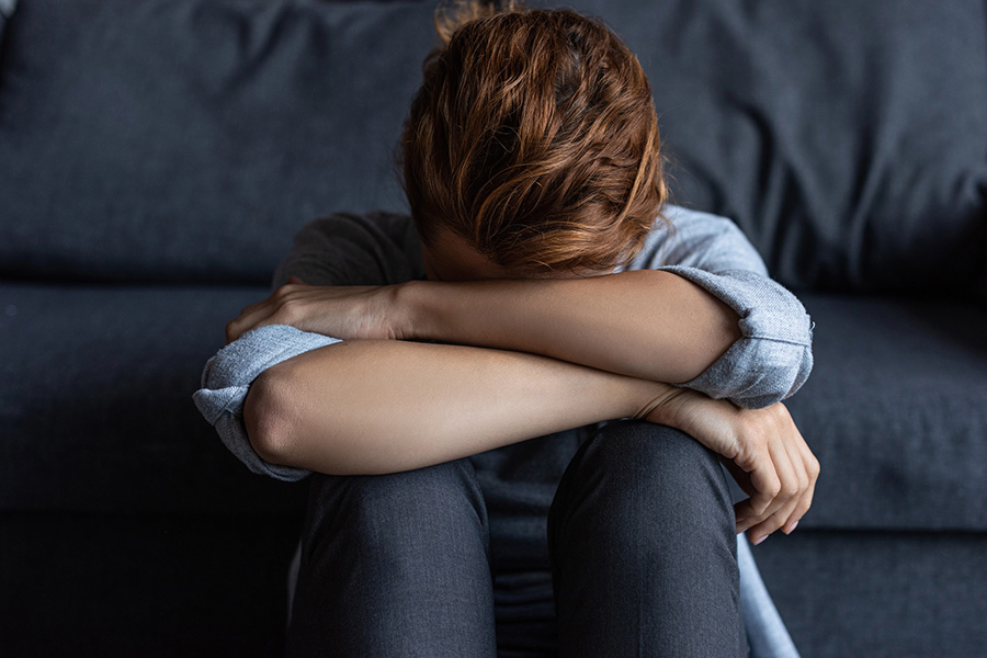 A distressed person sitting on a couch, symbolizing the emotional impact of childhood trauma and adult mental health challenges