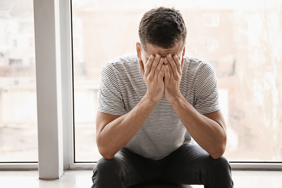 A distressed person sitting with their head in their hands, symbolizing fear of being alone and BPD-related emotional challenges.