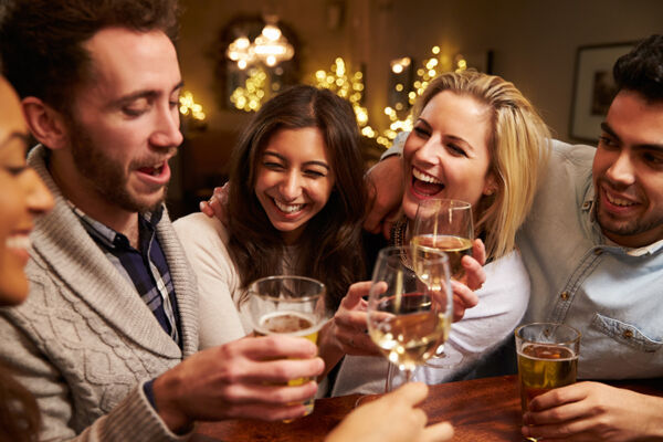 A group of friends drinking and laughing together, highlighting the social pressures of quitting alcohol.