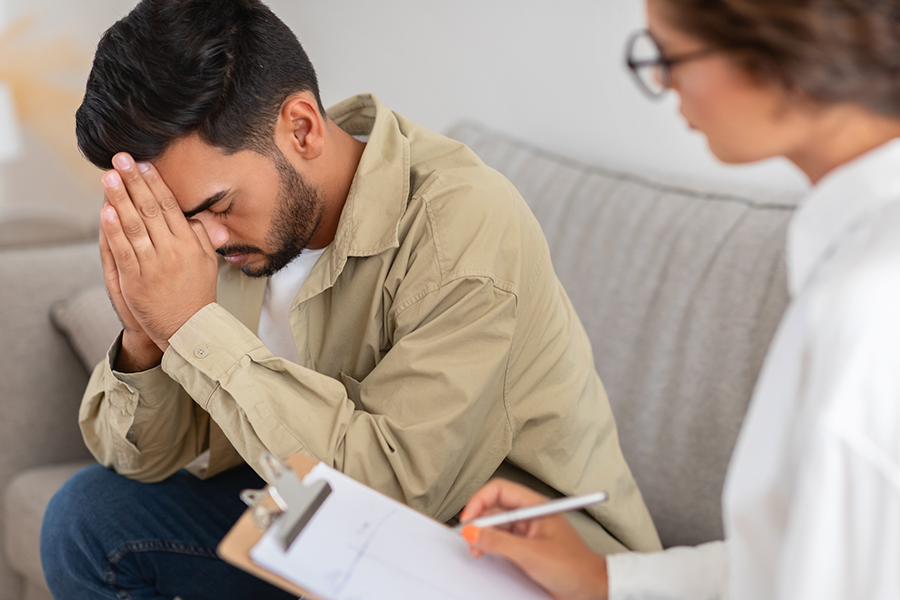 A man in distress sits with a therapist during an IOP alcohol rehab in Phoenix, receiving individual therapy for support and guidance.