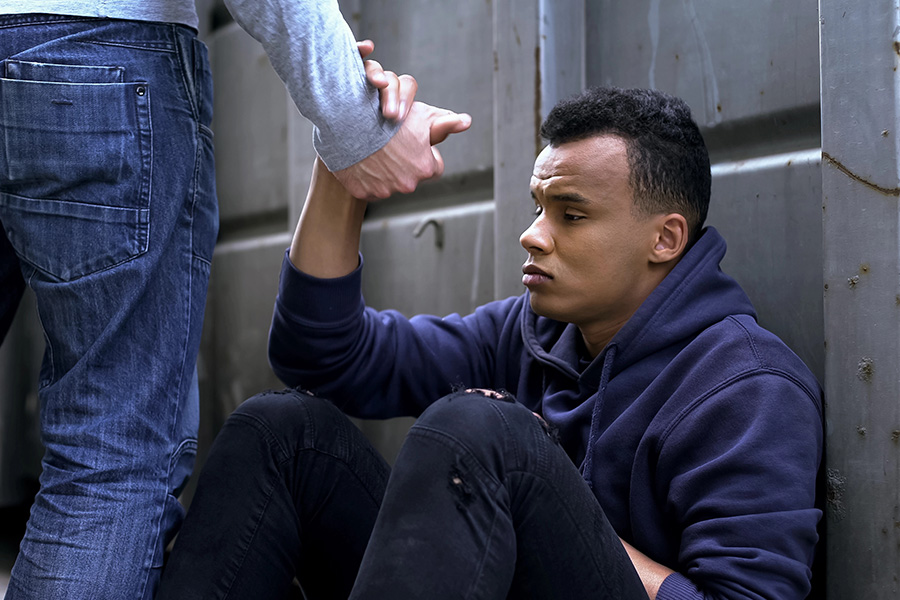 A person sitting on the ground receiving help, representing emotional support at a borderline personality disorder treatment center.