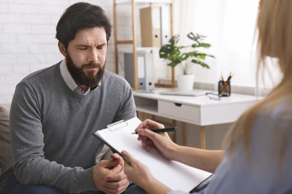 A stressed man talking to a mental health professional about sleep problems, highlighting the critical connection between mental health and sleep patterns