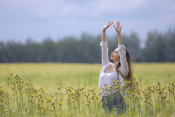 A woman joyfully raising her arms in a field of flowers, symbolizing the healing and freedom achieved through trauma recovery therapy