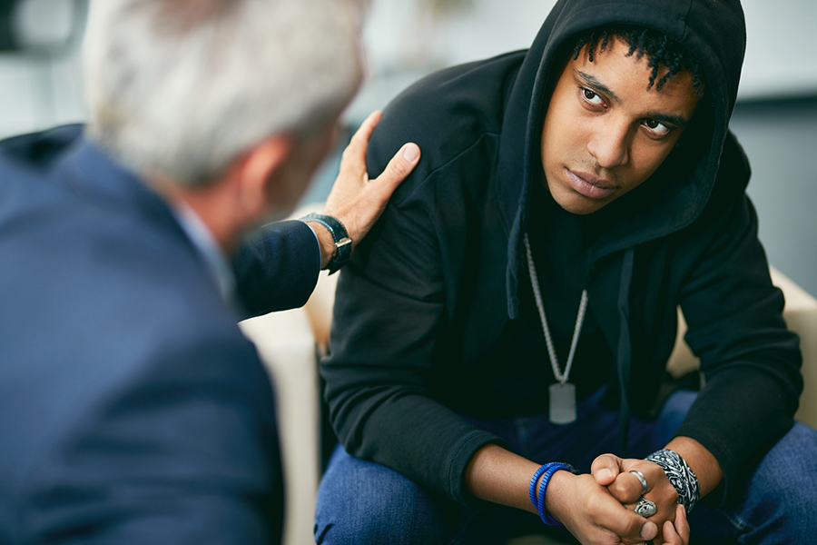 A young person in a hoodie receiving support, symbolizing the impact of childhood trauma on mental health and recovery