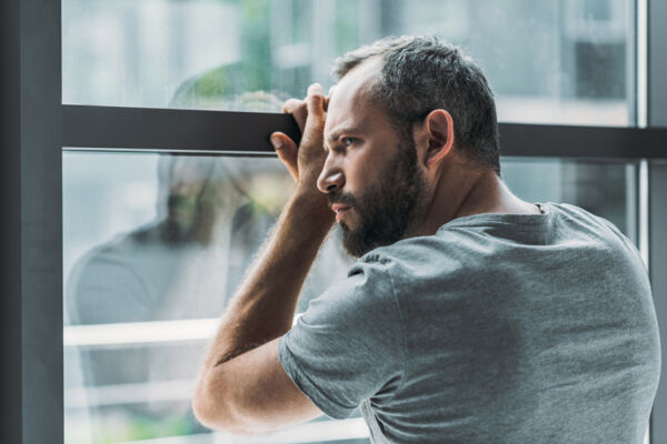 Adult male looking out the window suffering from depression, which is one of the addiction symptoms for cocaine