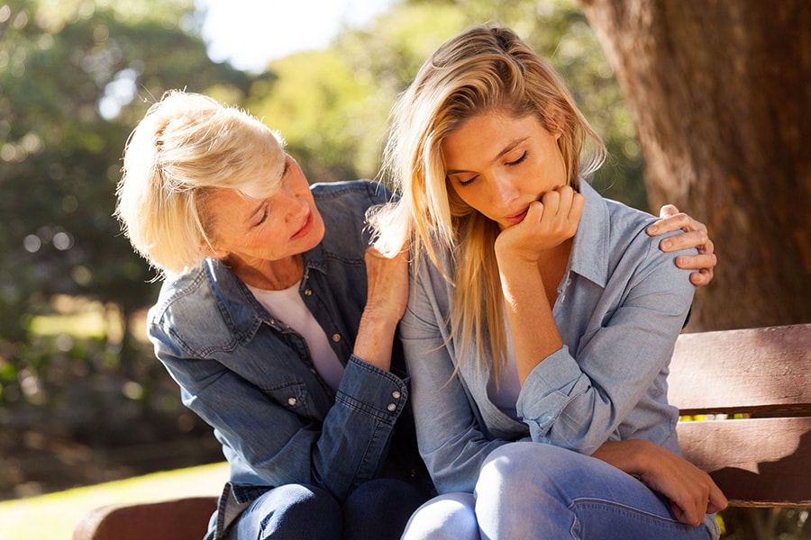 An older woman comforting a younger woman on a bench, symbolizing support for someone struggling with cocaine addiction