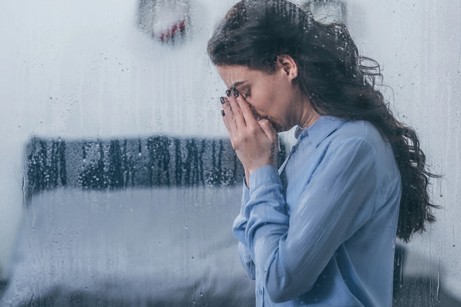 Distressed woman near a window symbolizing challenges of co-occurring disorder and avoidant personality disorder treatment