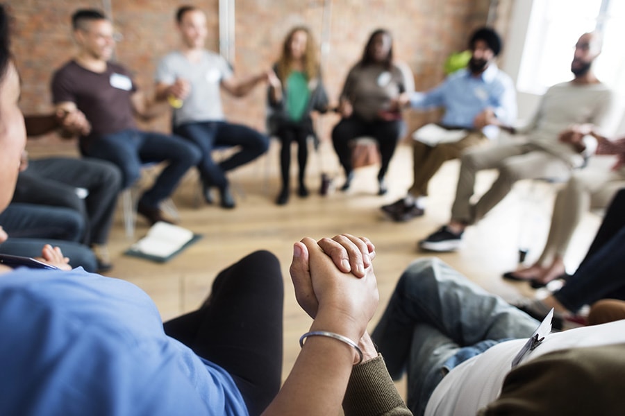 Diverse group of adults in a support group circle, discussing the 3 C's of Al Anon for emotional support