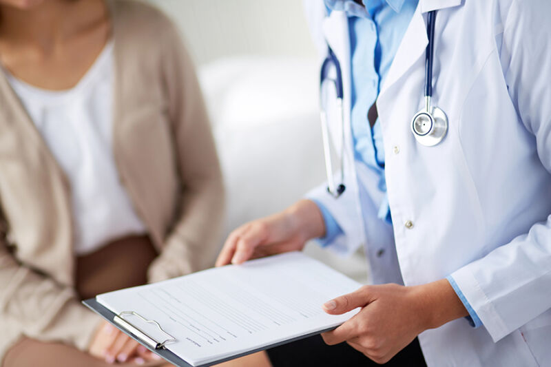 Doctor consulting patient about types of drug detox programs, clipboard in hand