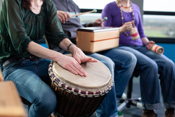 Group therapy session with individuals playing drums and percussion instruments, promoting recovery at PHP alcohol rehab in Phoenix