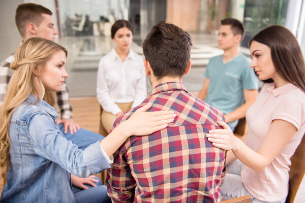 Group therapy session in a drug detox program, members supporting each other