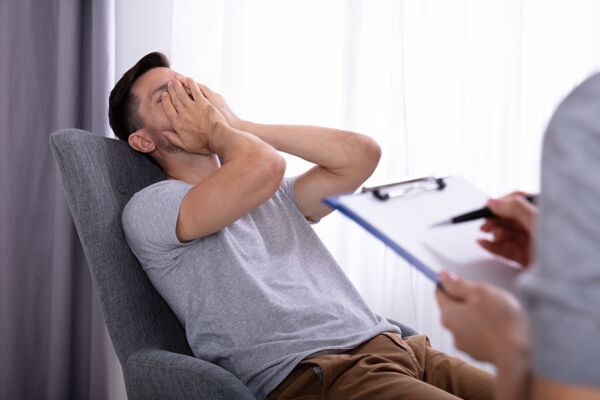 Man covering his face during individual therapy for mental health treatment