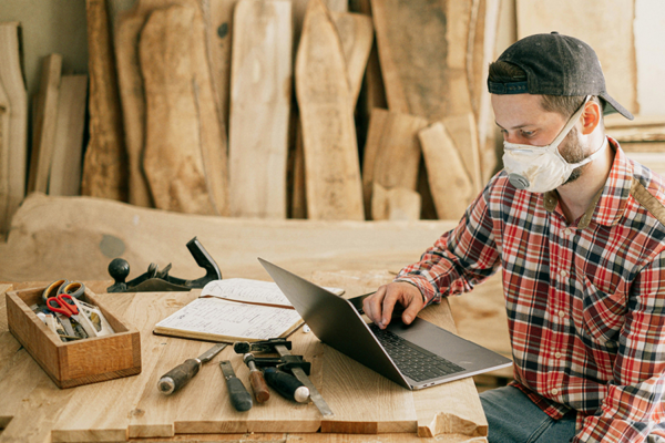 Man in workshop on laptop, integrating enjoying hobbies in recovery as part of addiction treatment programs