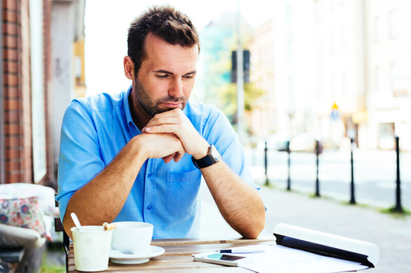 Man reviewing his in-network Cigna mental health coverage while sitting at a table with a cup of coffee