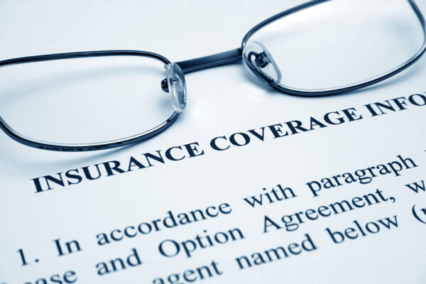 Reading glasses resting on top of a health insurance form document concept image for checking out drug or alcohol addiction treatment coverage