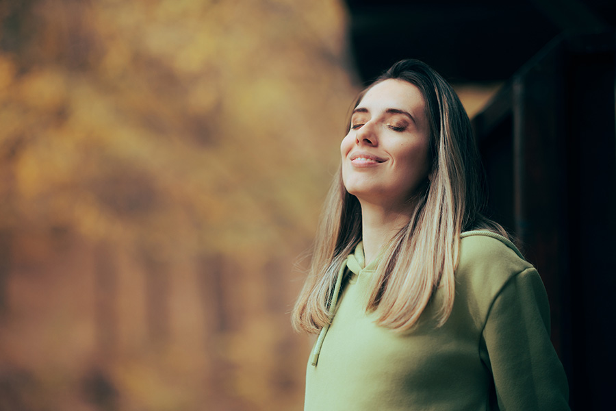 Serene woman practicing mindfulness breathing outdoors for personality disorder treatment in a natural autumn setting