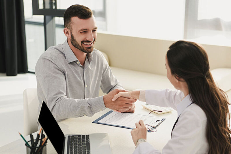 Smiling client shaking hands with the doctor about his Blue Cross Blue Shield Drug Rehab Coverage claim