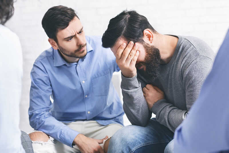 Two people comfort a distressed man showing what is a drug intervention