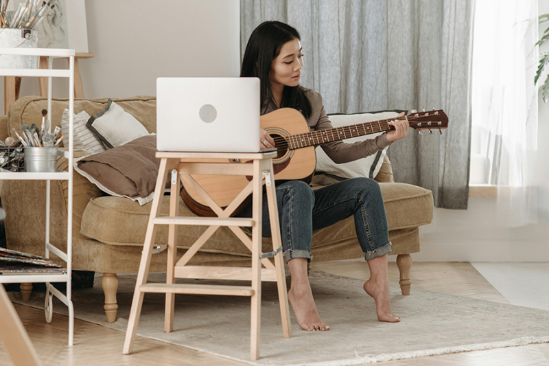 Woman enjoying hobbies in recovery by playing guitar at home