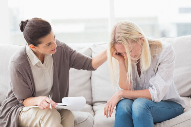 Sex addiction treatment therapist consoling her female patient after being diagnosed with compulsive sexual behavior.