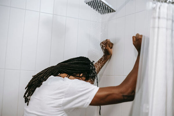 Young man suffering from anxiety disorder showering with clothes on in need of residential mental health treatment